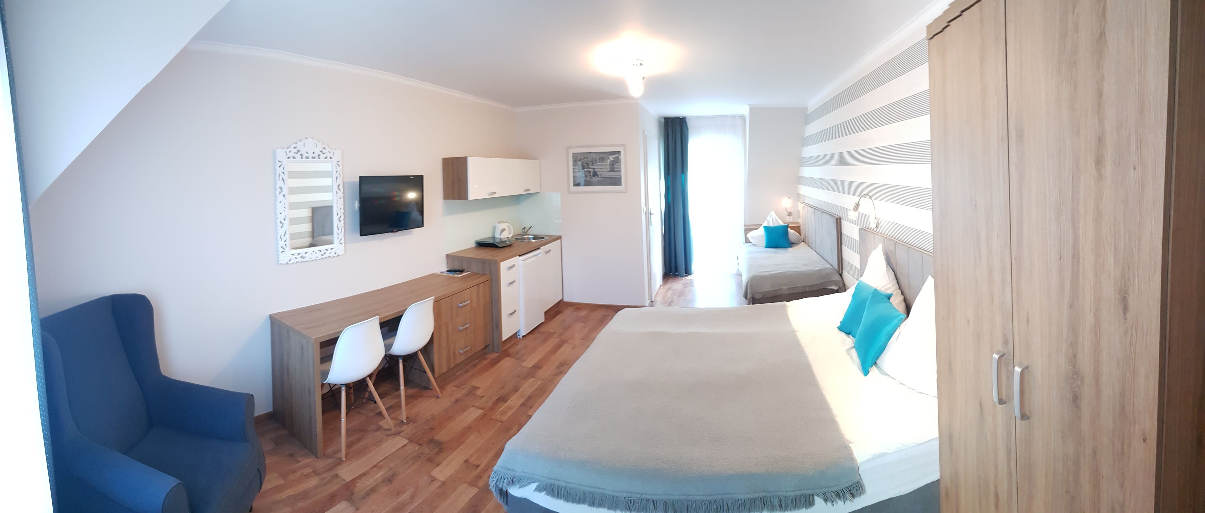 Una camera da letto con un letto, una scrivania con sedie, un armadio e un bagno sullo sfondo.