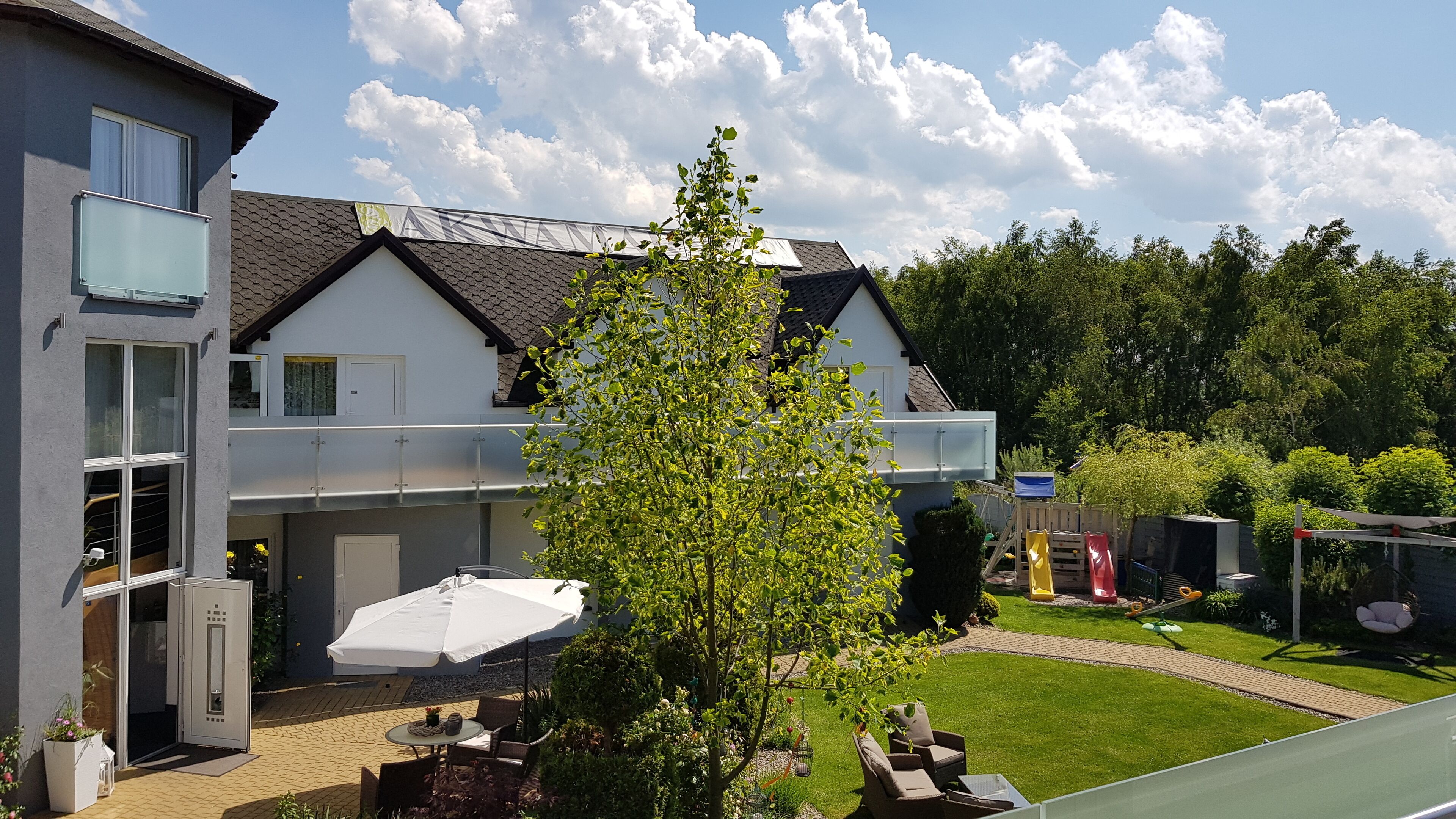 Une maison moderne dotée d’un patio couvert, d’un arbre et d’une pelouse bien entretenue.