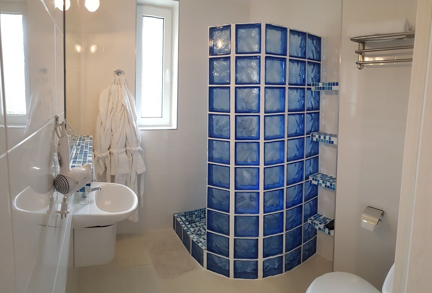 A bathroom with a glass shower enclosure, a sink, and a toilet.