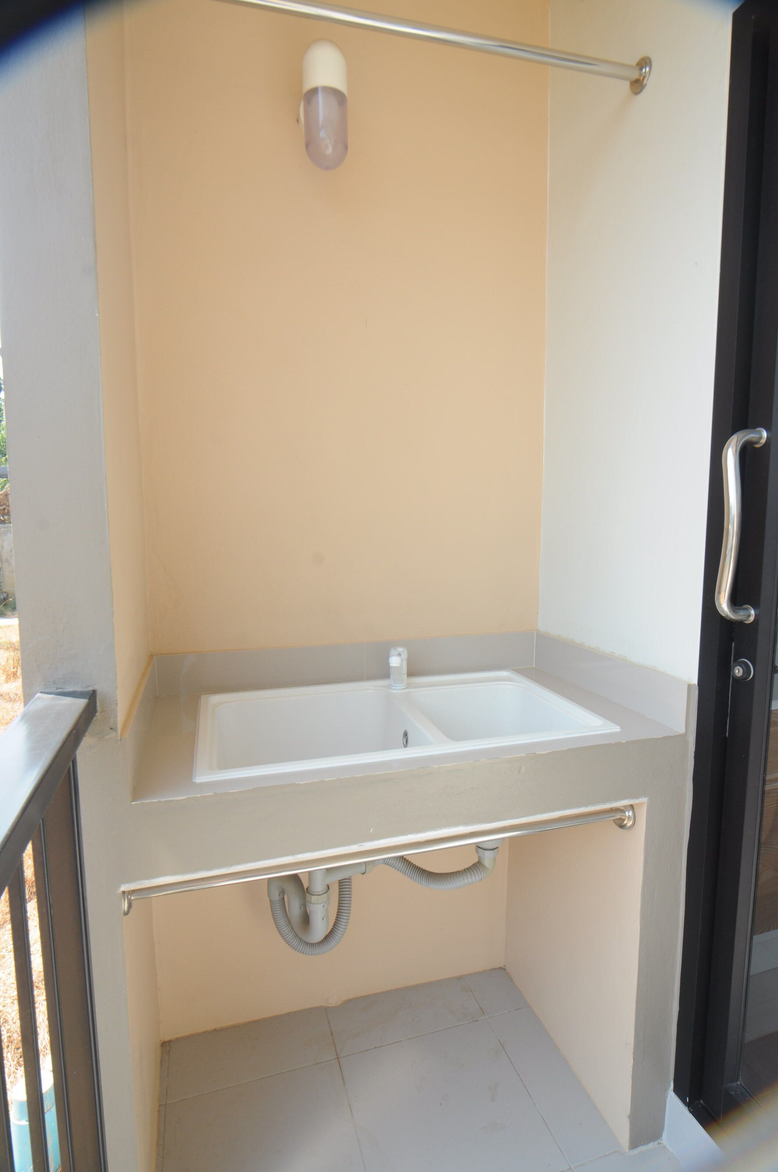 A small bathroom with a white sink and a handrail.