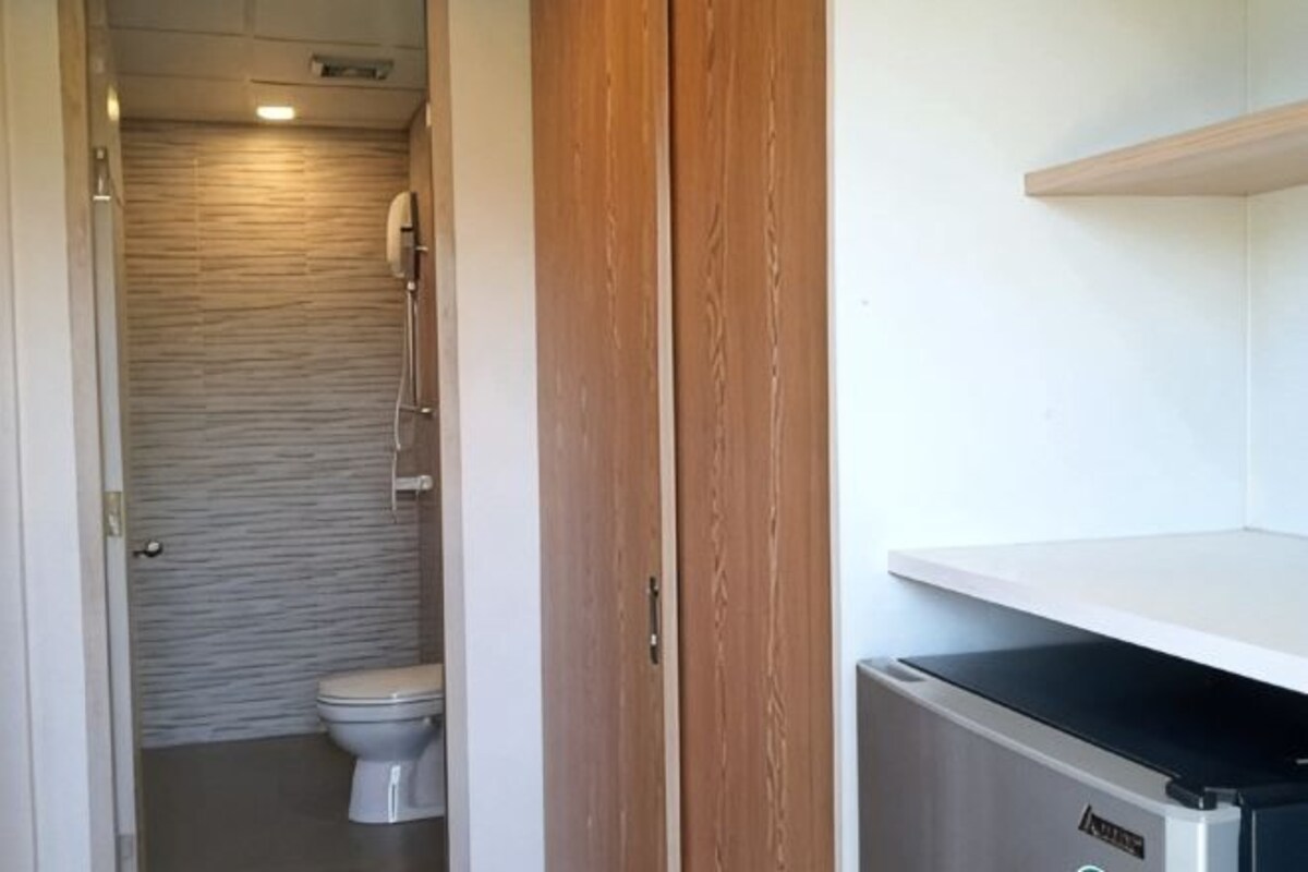 A bathroom with a toilet, shower, and a wooden door.