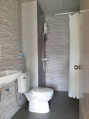 Un baño moderno con inodoro, lavamanos y ducha.