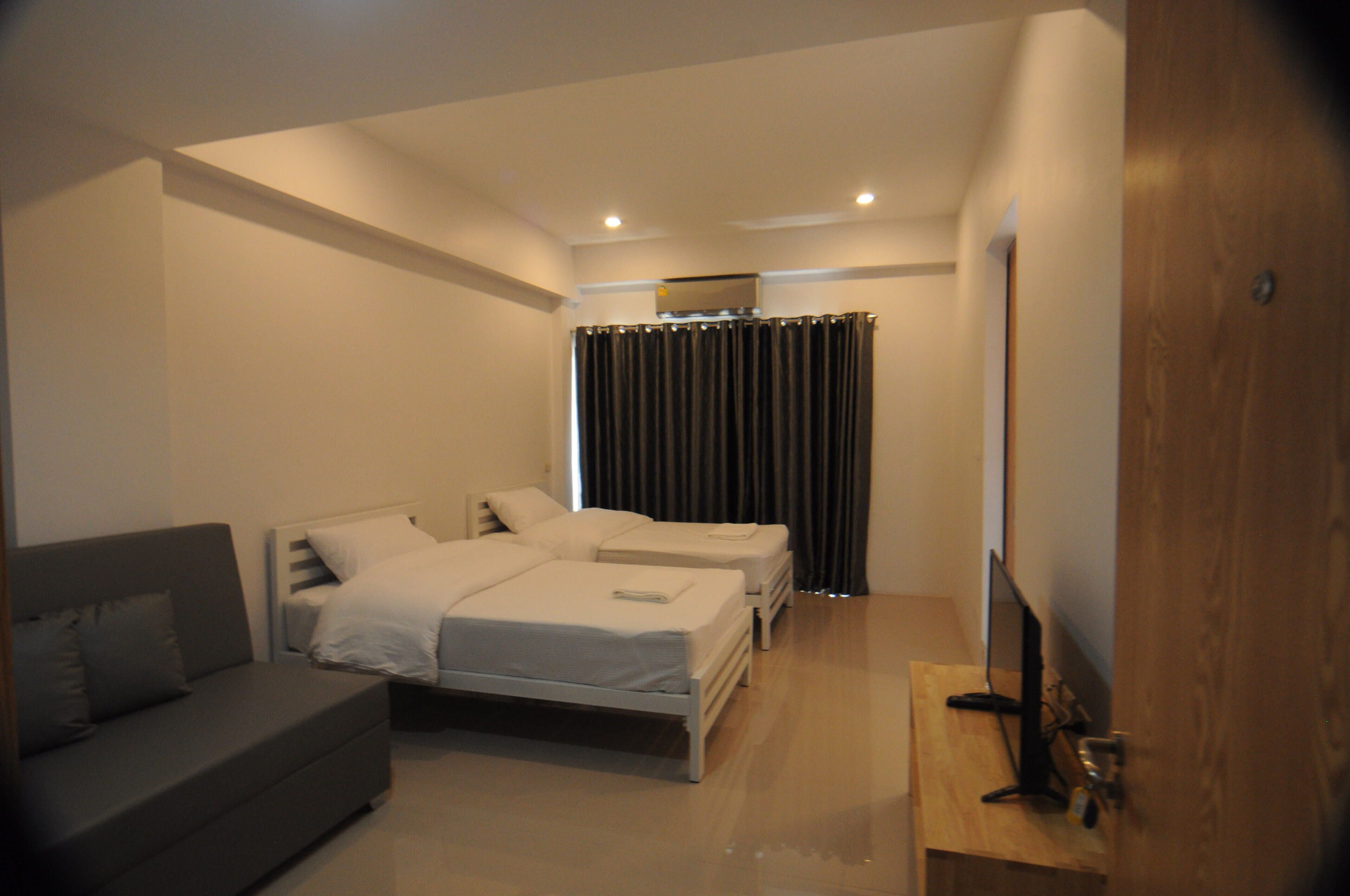 A modern bedroom with a bed, a sofa, and a TV.