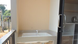 Un baño pequeño y cerrado con un lavamanos, un perchero para toallas y una puerta de vidrio que da a un espacio de almacenamiento.