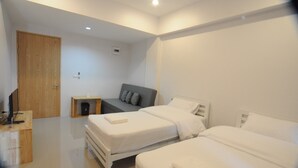 Un dormitorio moderno con dos camas, un escritorio de madera y un sofá gris.