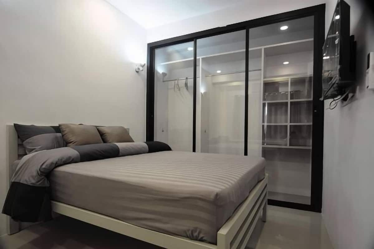 Un dormitorio con cama, armario y televisor.