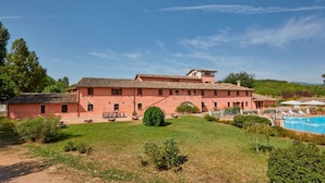 A large, two-story building with a tiled roof, surrounded by a well-maintained lawn and a swimming pool. - In the middle of nature Apartment. Fireplace and Olives trees view. Zaffiro (Spoleto)