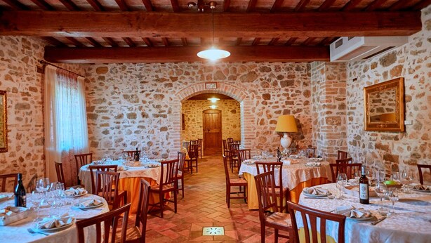 A restaurant with stone walls and wooden beams, featuring multiple tables set for dining. - In the middle of nature Apartment. Fireplace and Olives trees view. Zaffiro (Spoleto)