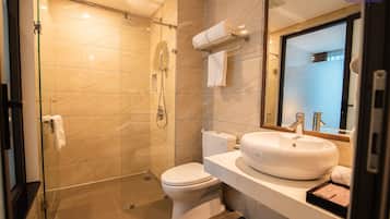 Un baño moderno con ducha envuelta en vidrio, inodoro y lavabo con espejo arriba.
