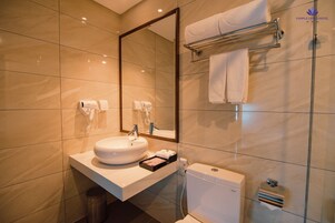 A modern bathroom with a large mirror, a sink, a towel rack, and a toilet.