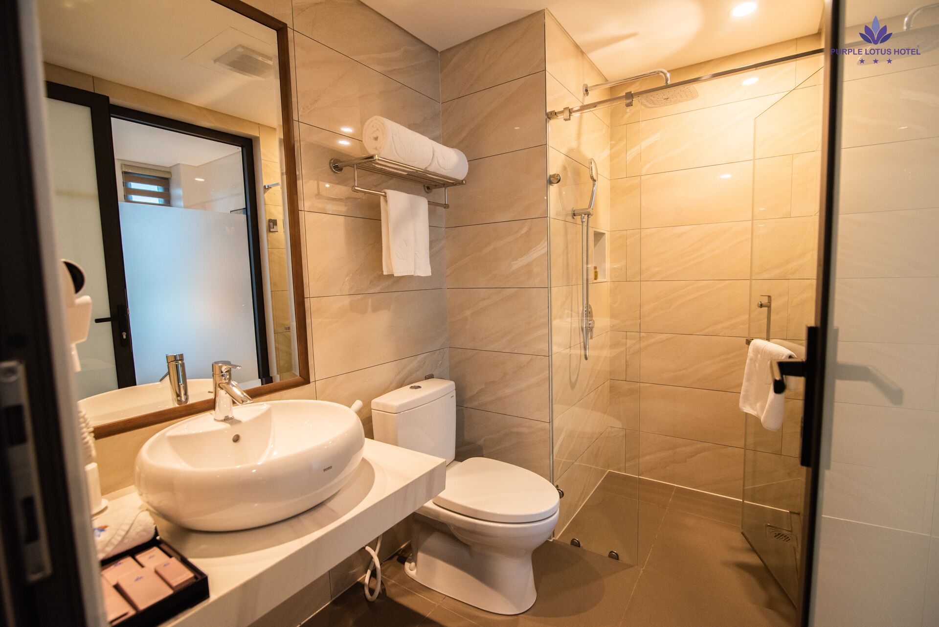 A modern bathroom with a large sink, toilet, and glass-enclosed shower.