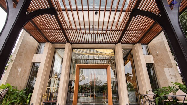 A modern hotel entrance with a glass canopy and a reception desk. - Purple Lotus Hotel (Hai Phong)