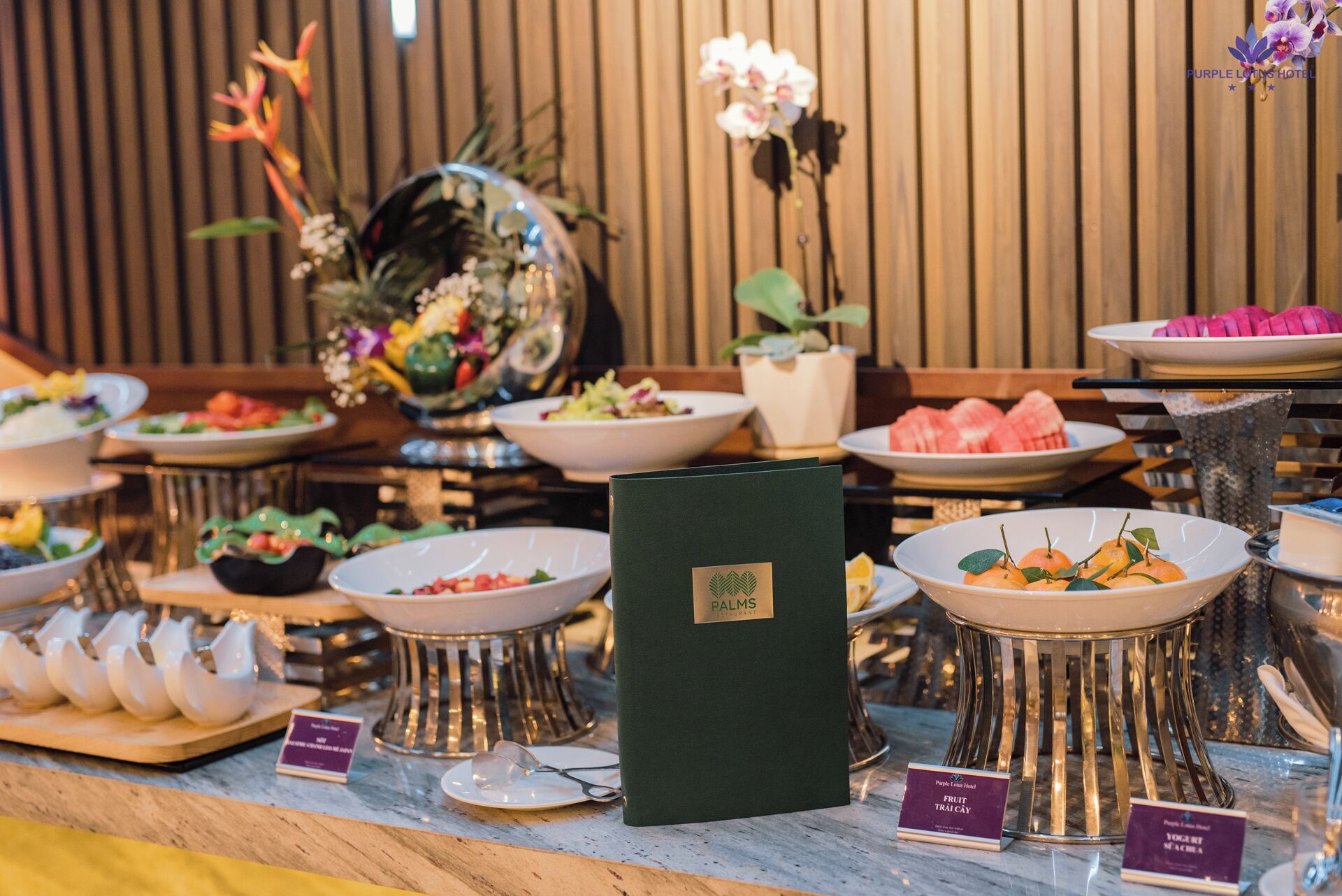 Ein Buffet mit verschiedenen Speisen, einer grünen Menükkarte und einem Holzhintergrund.