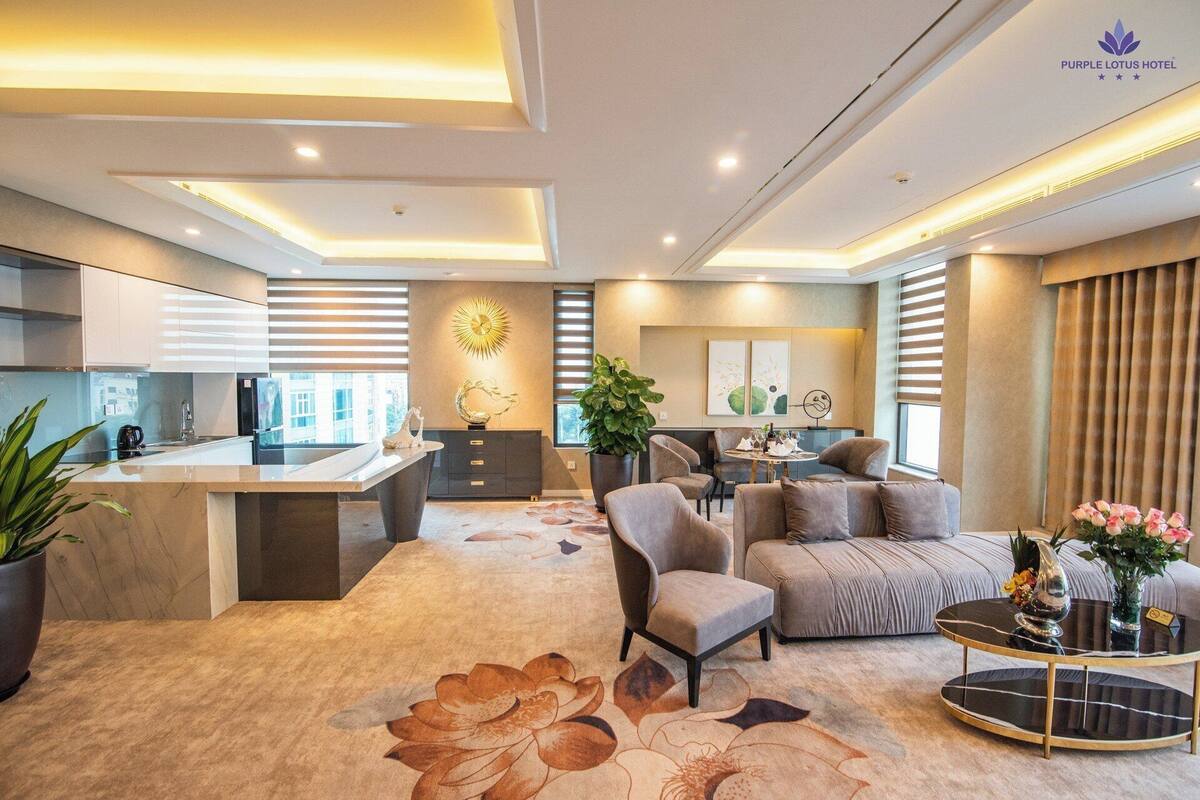 Une chambre d’hôtel moderne dotée d’un coin cuisine, d’un espace repas et d’un coin salon avec un canapé et des fauteuils.