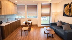 A modern hotel room with a kitchen, dining area, and seating space. - Purple Lotus Hotel (Hai Phong)