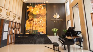 A lobby with a grand piano, a wall with clocks indicating different cities, and a large floral mural. - Purple Lotus Hotel (Hai Phong)