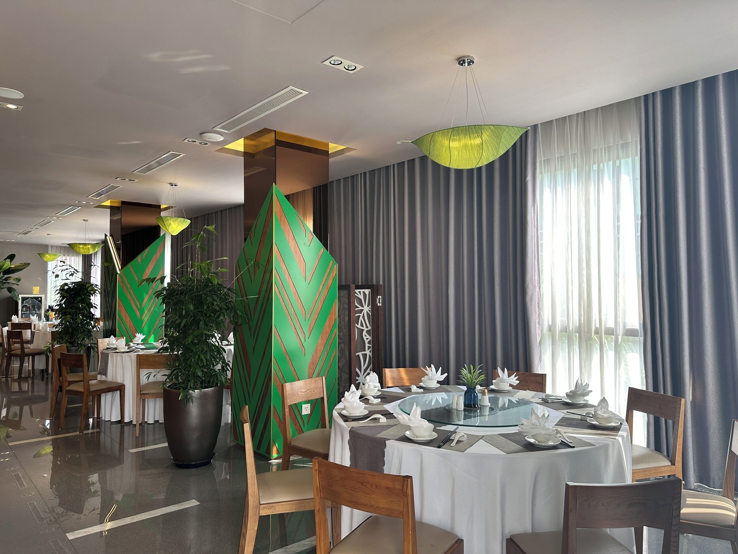 A modern dining area with a round table, chairs, and a decorative green panel.