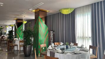A modern dining area with a round table, chairs, and a decorative green panel.