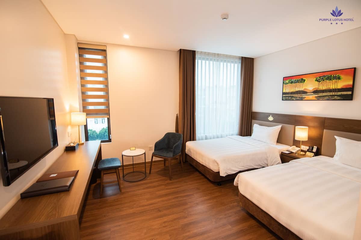 Une chambre d’hôtel avec deux lits, un bureau, une chaise, une télévision et un tableau au mur.
