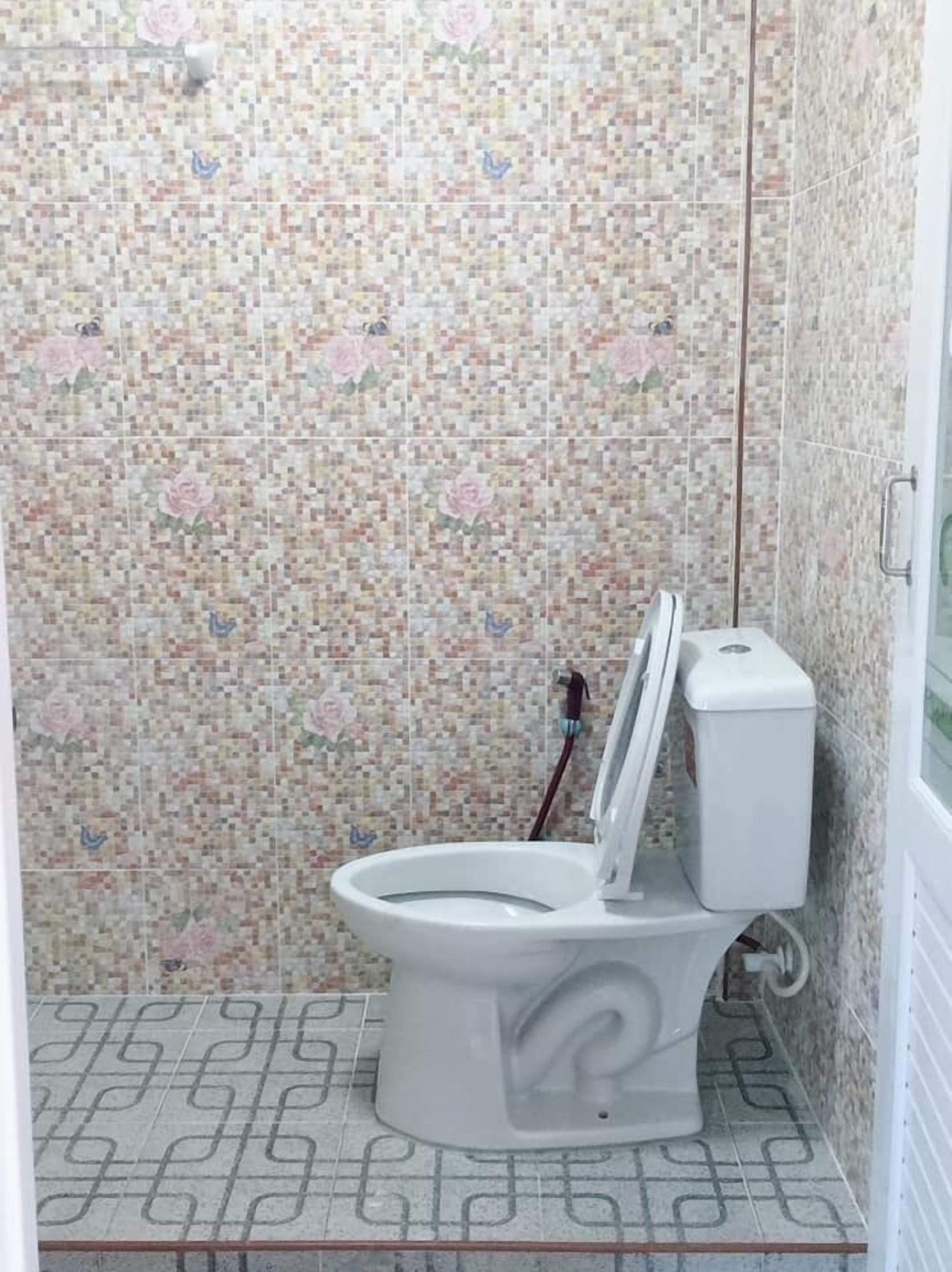 Un baño con inodoro, ducha y suelo de baldosas.