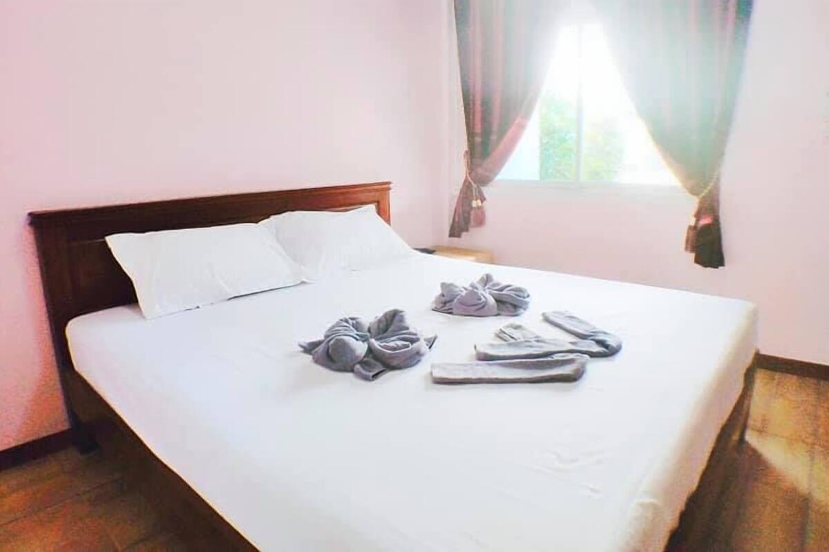 A neatly made bed with white linens and towels arranged on the bed.
