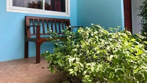A blue exterior wall with a wooden bench and a window. - Reuan Jao Ngao Resort (Maha Rat)