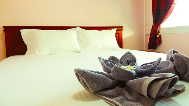 A neatly made bed with white linens and a towel arrangement in the center. - Reuan Jao Ngao Resort (Maha Rat)