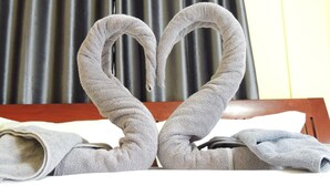 A bed with a heart-shaped towel arrangement. - Reuan Jao Ngao Resort (Maha Rat)