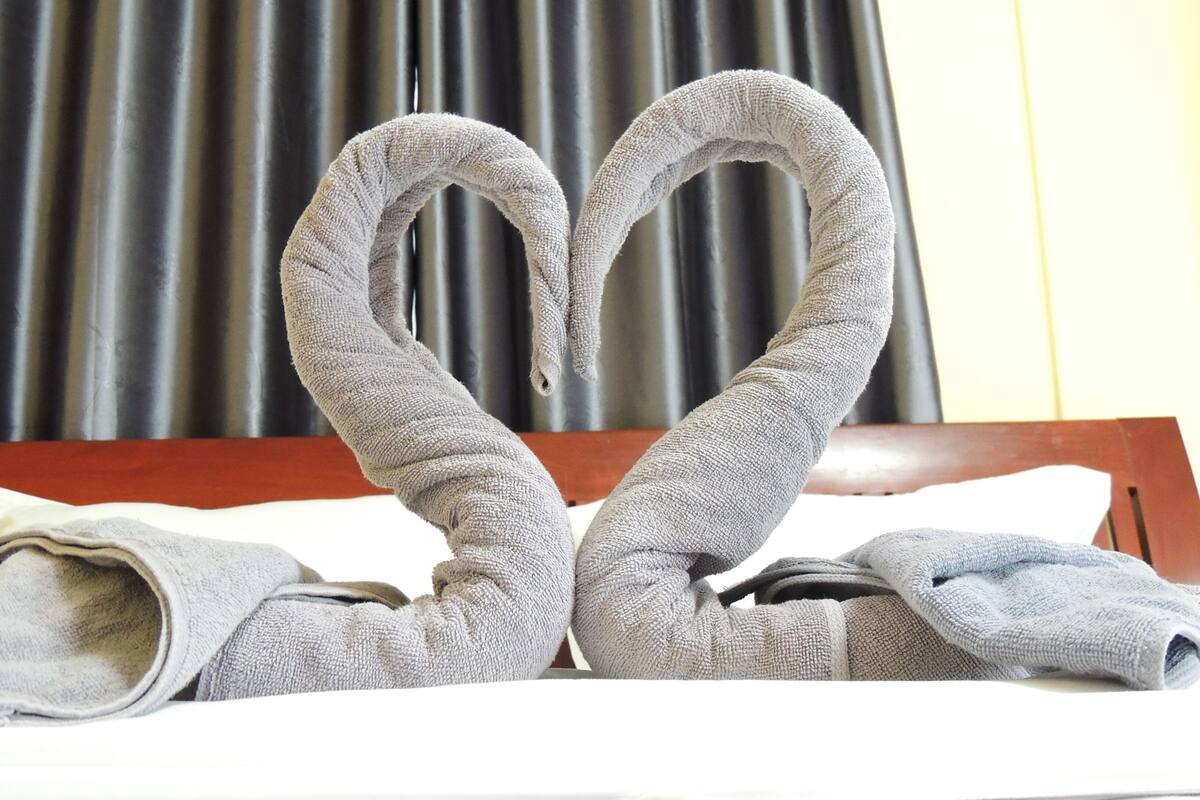 A bed with a heart-shaped towel arrangement.