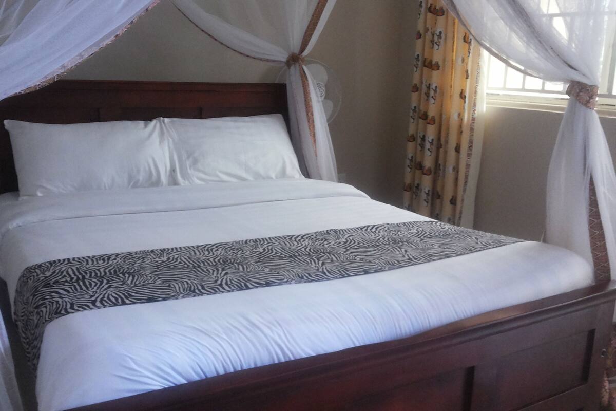 A bed with a canopy, a zebra-patterned bedspread, and curtains with a pattern.