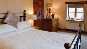 A bedroom with a bed, bedside lamp, dresser, window, and wooden beams. - 3 bedroom accommodation in Hebden, near Grassington (Hebden, near Grassington)