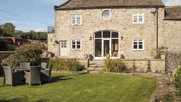A stone building with a large arched entrance, multiple windows, and a well-maintained lawn. - 3 bedroom accommodation in Hebden, near Grassington (Hebden, near Grassington)