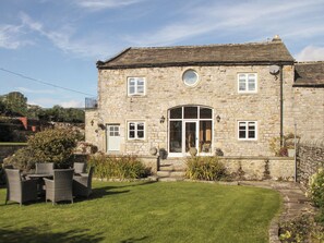 A stone building with a large arched entrance, multiple windows, and a well-maintained lawn. - 3 bedroom accommodation in Hebden, near Grassington (Hebden, near Grassington)