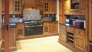 A kitchen with wooden cabinets, a stove, and a countertop. - 3 bedroom accommodation in Hebden, near Grassington (Hebden, near Grassington)