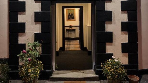 The Griffin Inn entrance with a black and white facade, a welcoming archway, and a framed picture above the door. - The Griffin Inn (Brecon)