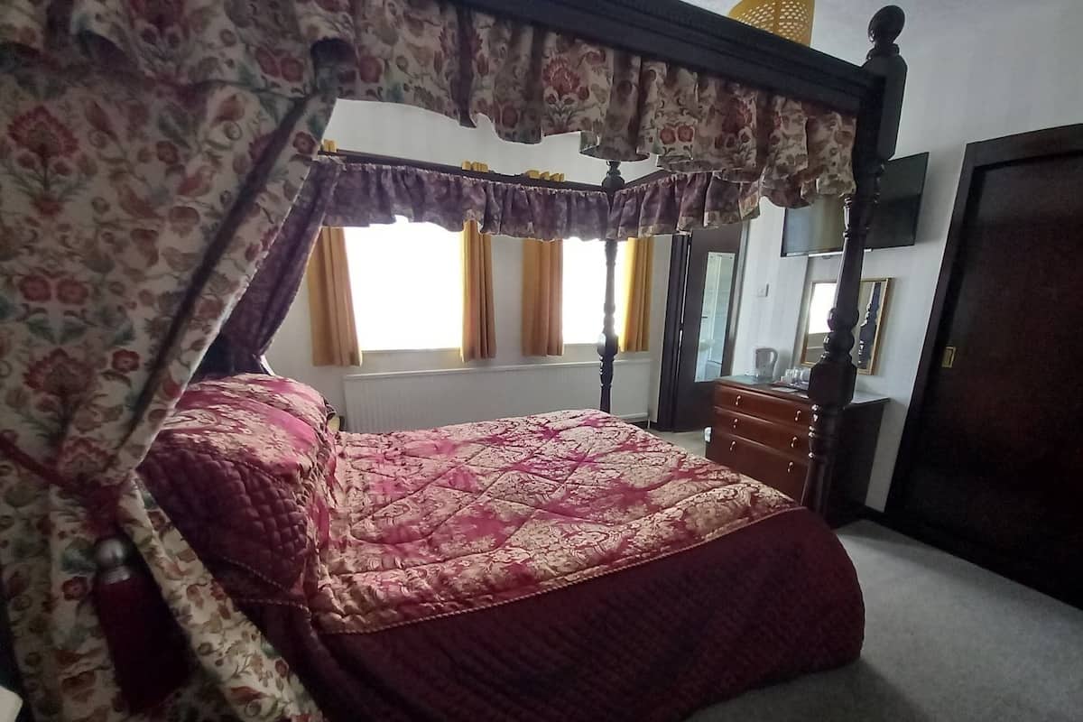 Um quarto com uma cama de dossel, uma cômoda de madeira e um espelho na parede.