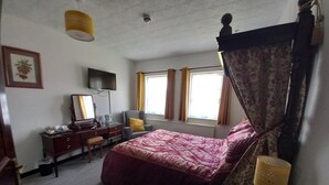 A bedroom with a four-poster bed, a desk with a chair, a television, and a window with curtains. - The Griffin Inn (Brecon)