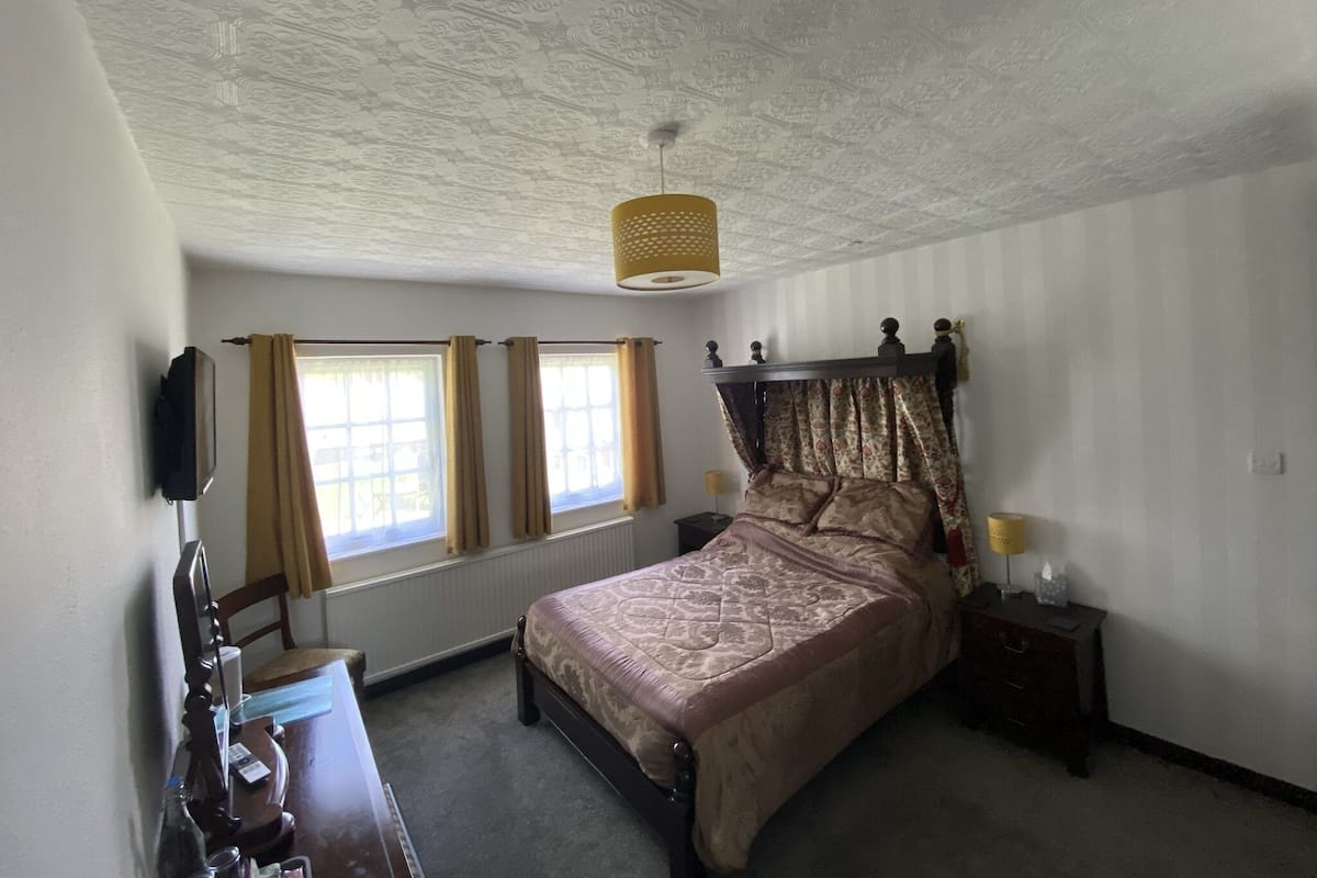 Um quarto com cama de dossel, cômoda, espelho e teto com padrão decorativo.