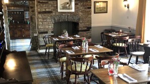 A cozy restaurant with wooden tables and chairs, a stone fireplace, and a checkered floor. - The Griffin Inn (Brecon)