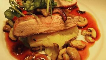 A plate of food with a piece of meat, mushrooms, and greens.