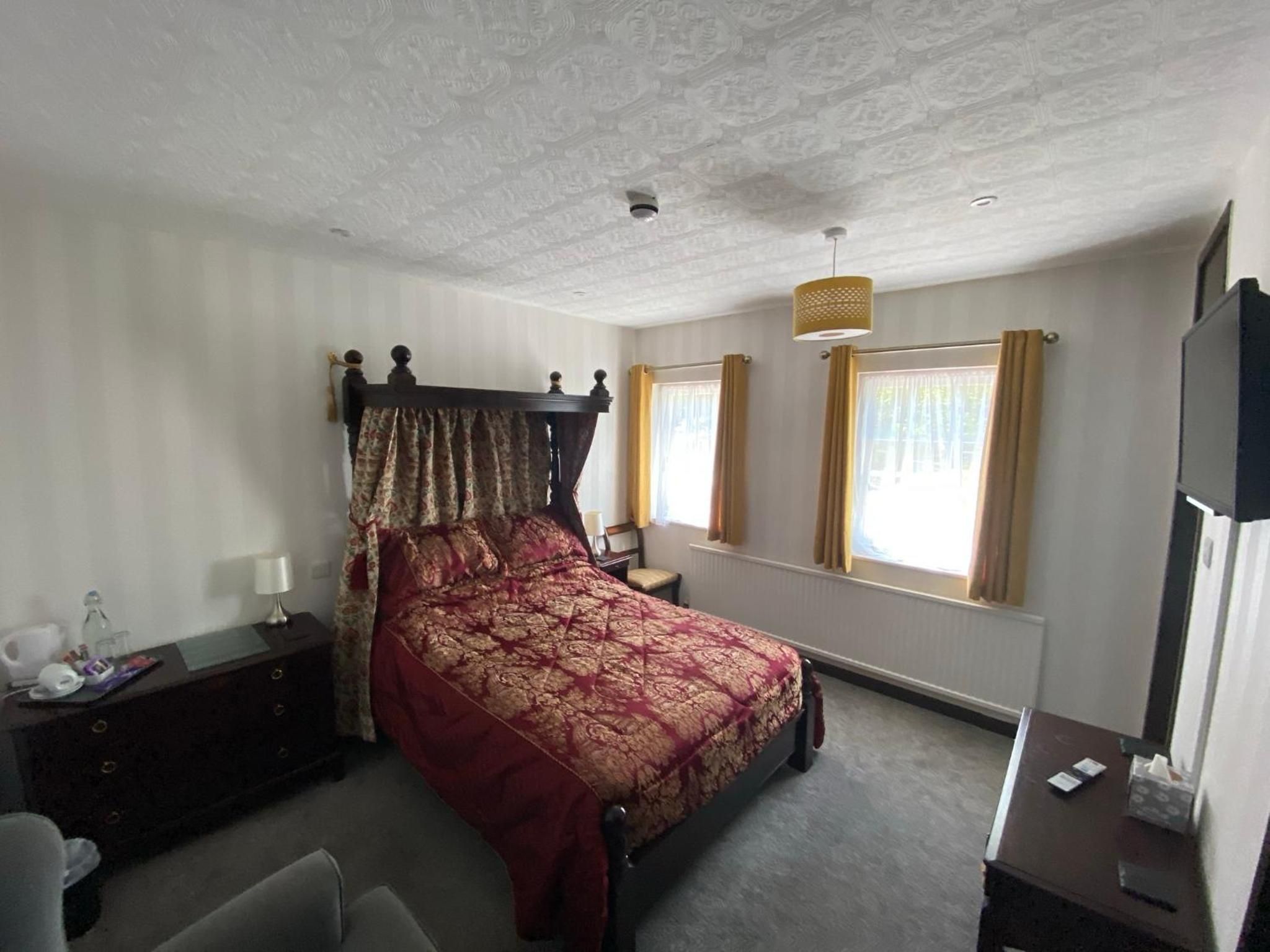 Una camera da letto con un letto a baldacchino, un comodino, una sedia, una scrivania, una lampada e una finestra con tende.