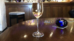 A bar setting with a glass of white wine on a wooden table, a coaster, and a blue coaster with a logo. - The Griffin Inn (Brecon)