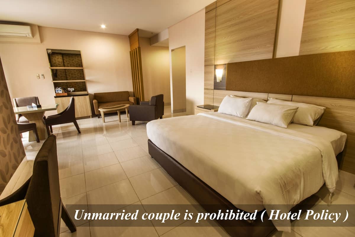 Ein Hotelzimmer mit einem großen Bett, einem Schreibtisch, einer Couch und einem kleinen Tisch.
