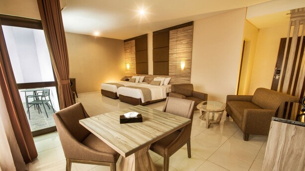 Une chambre d’hôtel comprenant un coin repas, un canapé, un lit avec deux oreillers et une petite table.