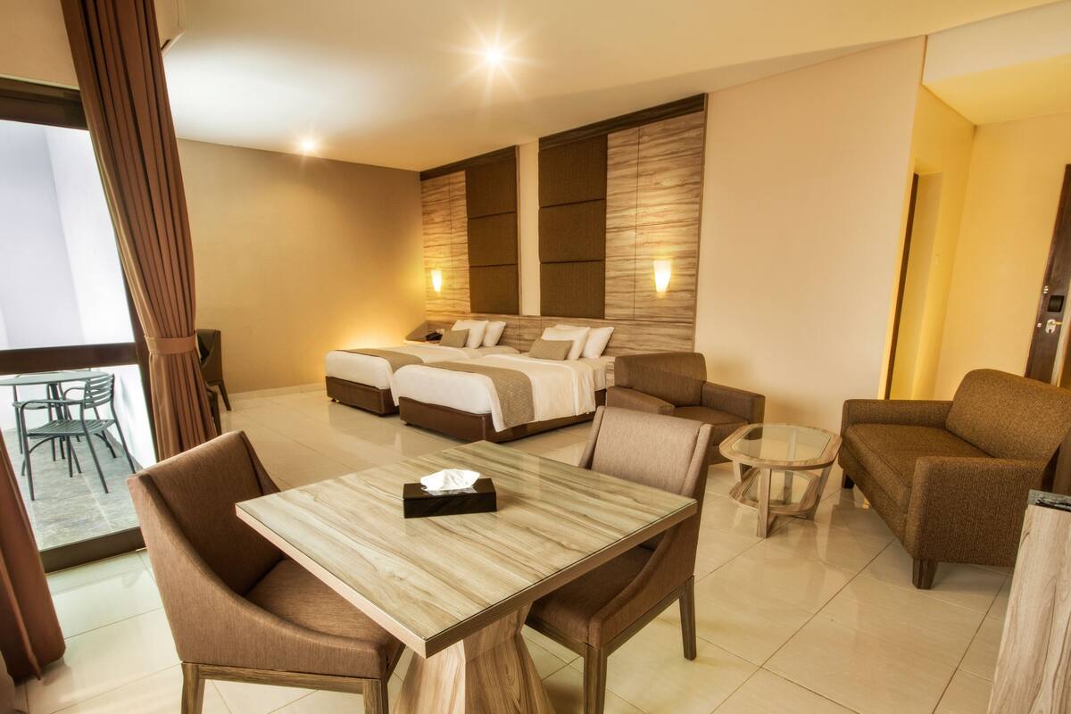 Une chambre d’hôtel comprenant un coin repas, un canapé, un lit avec deux oreillers et une petite table.
