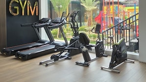 Une salle de sport équipée de tapis de course, de vélos elliptiques et d’une enseigne fixée au mur sur laquelle on peut lire « SALLE DE SPORT ».