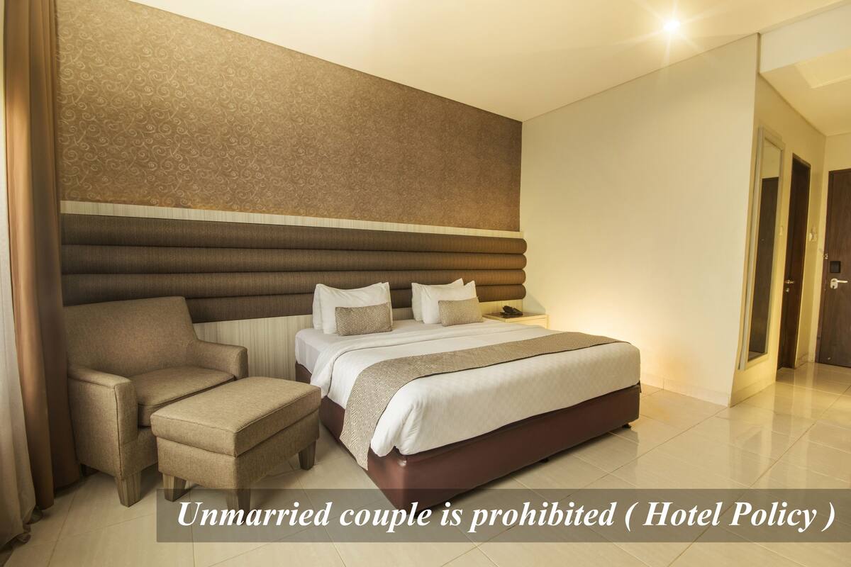 Ein Hotelzimmer mit einem Bett, einem Sessel und einem Nachttisch.