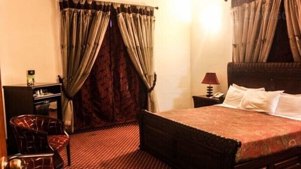 Una camera d'albergo con un letto, una scrivania, una sedia e tende.