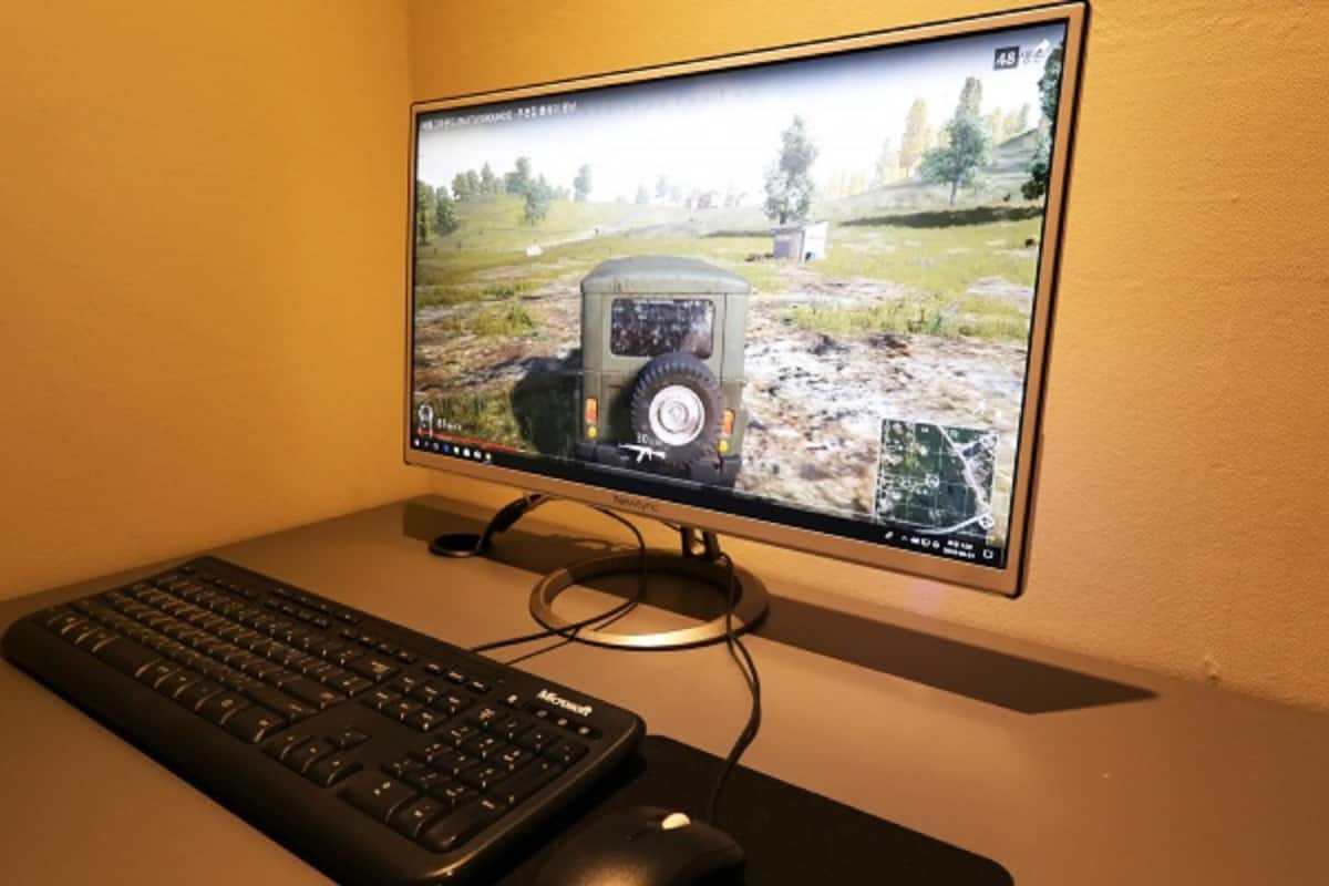 A computer monitor displaying a video game with a vehicle on a map, a keyboard, and a mouse on a desk.