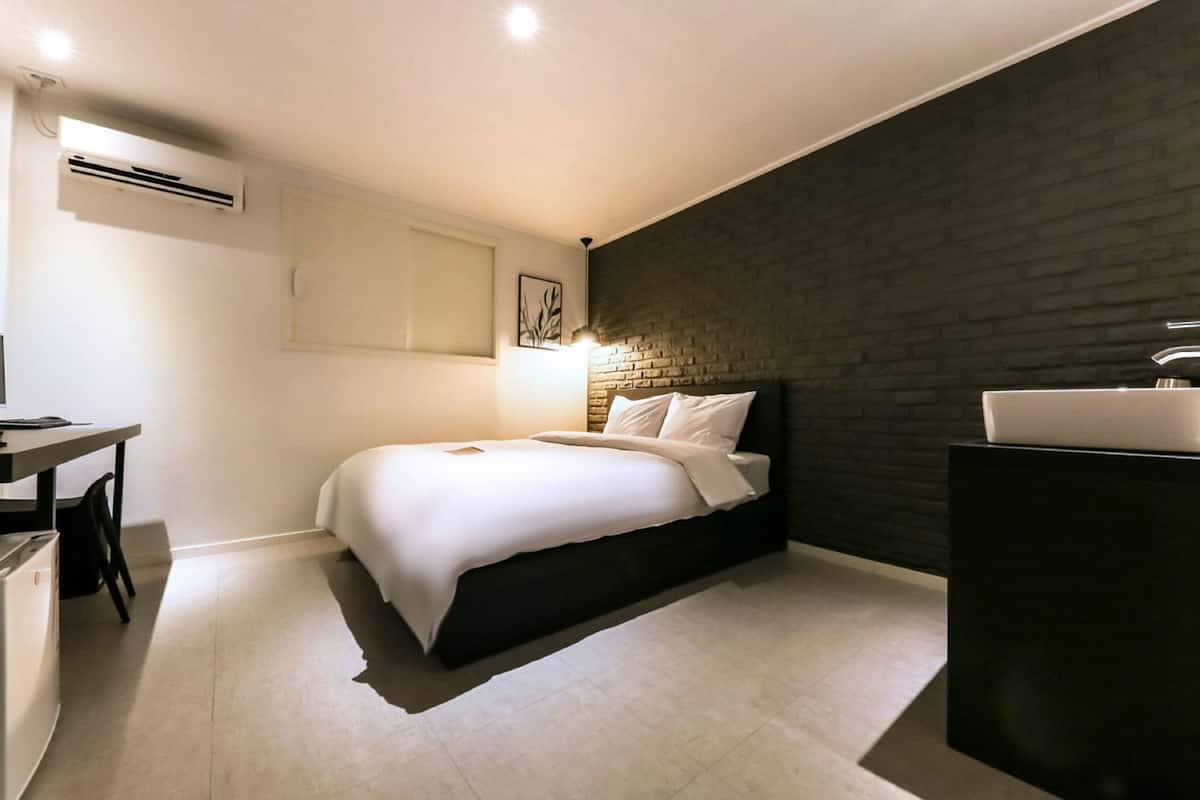 A modern bedroom with a bed, a desk, and a sink.